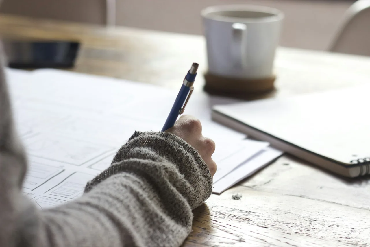 Student calculating grades at a desk with notes and a pencil